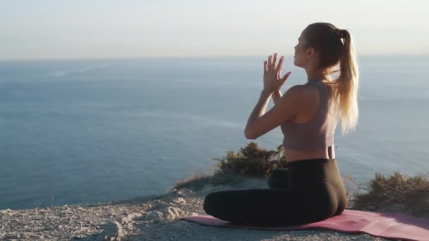 La mujer se sienta en posición de yoga de loto en la esterilla y medita al aire libre, en cámara lenta — Vídeos de Stock