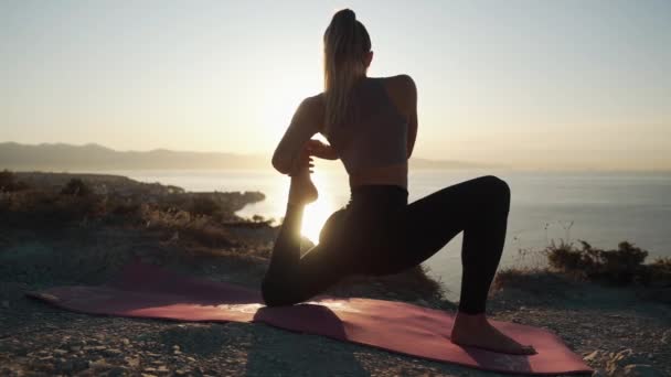 Σιλουέτα της γυναίκας κάνει γυμναστική γιόγκα, τέντωμα στην ακτίνα του ήλιου, αργή κίνηση — Αρχείο Βίντεο