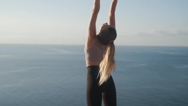 Mujer hace ejercicio de fitness al aire libre al amanecer con vista al mar, cámara lenta — Vídeo de stock