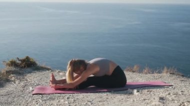 Kadın egzersizleri yapar ve deniz manzarası ile sabah uzanır, yavaş hareket