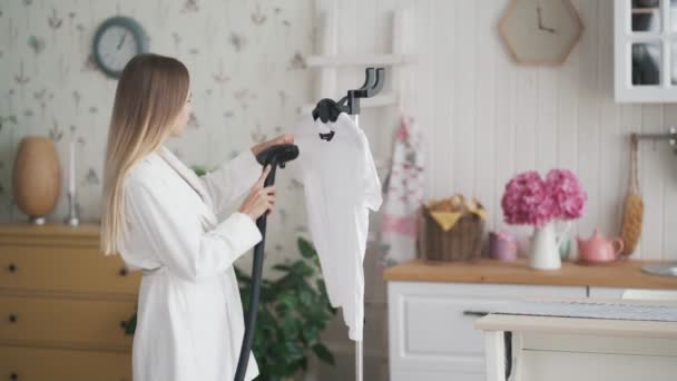 Mulher bonita em roupão de banho branco usando sistema de vapor para passar roupas — Vídeo de Stock