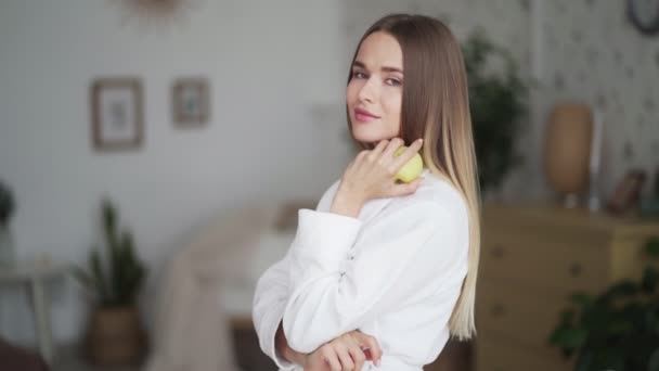 Retrato de mujer mirando a la cámara, sonriendo, sosteniendo manzana verde en su mano — Vídeo de stock