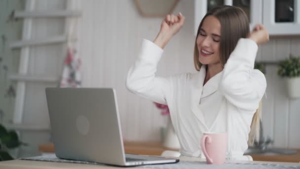 Mujer joven trabaja en el ordenador portátil, recibe noticias positivas en el correo electrónico, se siente feliz, emocionado — Vídeo de stock