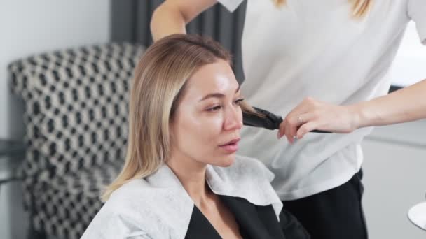 Крупним планом перукар розчісує пасма волосся клієнта в салоні краси, повільний рух — стокове відео