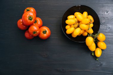 Siyah ahşap arka plan üzerinde kase içinde sarı ve kırmızı kiraz domates üst görünümü
