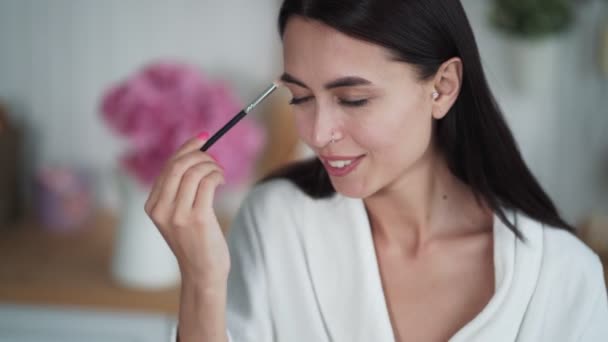 Porträtt av vacker kvinna gör smink, använda borste för att sätta ögonskuggor på hennes öga — Stockvideo