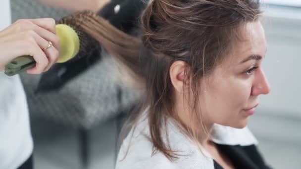 Coiffeur sèche femme cheveux humides avec sèche-cheveux après la coupe, au ralenti — Video