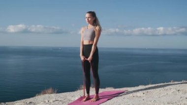 Kadın açık havada lastik bantlar ile egzersiz yapar, vücudunu trenler, yavaş hareket