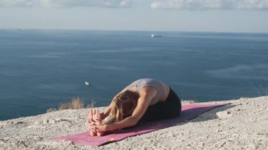 Kadın egzersizleri yapar ve deniz manzarası ile sabah uzanır, yavaş hareket