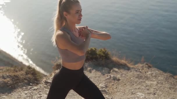 Frau duckt sich im Freien in Matten, trainiert ihren Körper, mit Meerblick, Zeitlupe — Stockvideo