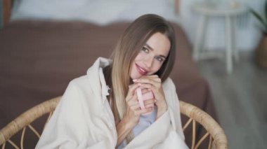 Ekoseye sarılı gülümseyen kadın portresi sıcak çay içer, kameraya bakar.