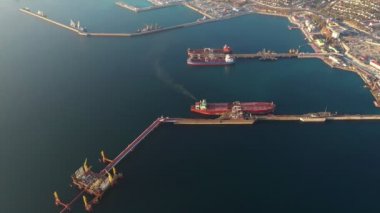 Endüstriyel şehrin deniz limanındaki petrol yatağının hava manzarası, arka planda tanker