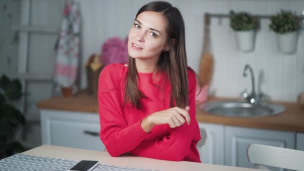 Portrait de jeune femme mignonne se trouve dans la cuisine à la maison, regarde la caméra, smileys — Video