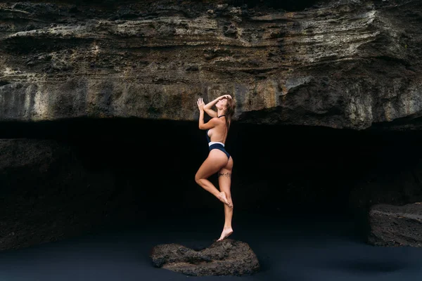 Sexy meisje poses in blauwe badpak in de buurt van Cave on Black Sand Beach, concept Travel — Stockfoto