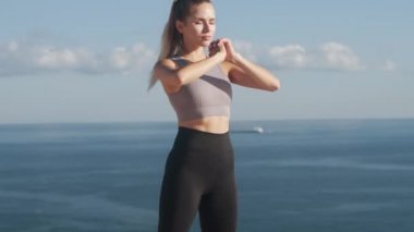 Kadın açık havada paspas crouches yapar, deniz manzaralı, yavaş hareket ile vücudunu trenler