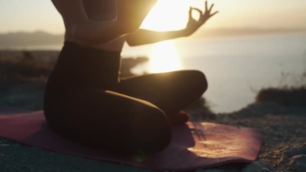 Teil des weiblichen Körpers sitzt in Lotusposition, macht Yoga-Übungen, meditiert — Stockvideo