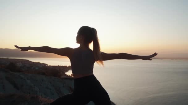 Silueta de mujer practica yoga y haciendo estiramientos al amanecer, cámara lenta — Vídeos de Stock