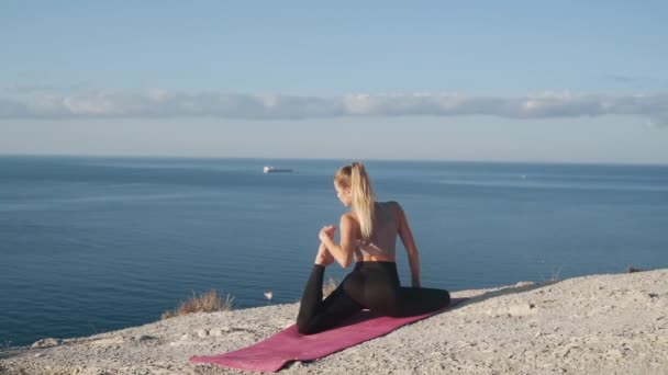 Mujer haciendo ejercicio de yoga en la cima de la montaña, mar sobre fondo, cámara lenta — Vídeo de stock