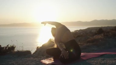 Kadın uygulamaları yoga silueti ve gün doğumunda germe yapıyor, yavaş hareket