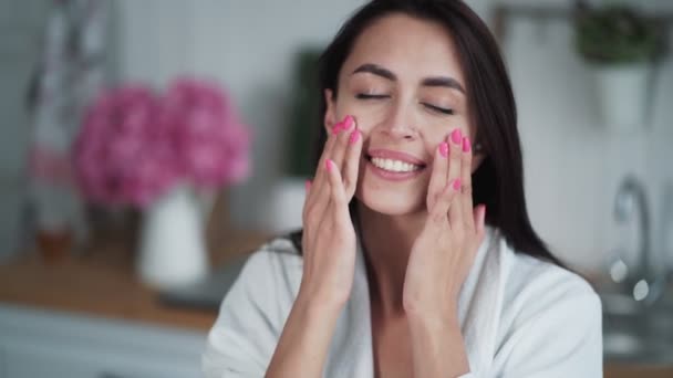 Портрет молодої жінки, що застосовує крем і робить масаж обличчя, природна краса — стокове відео