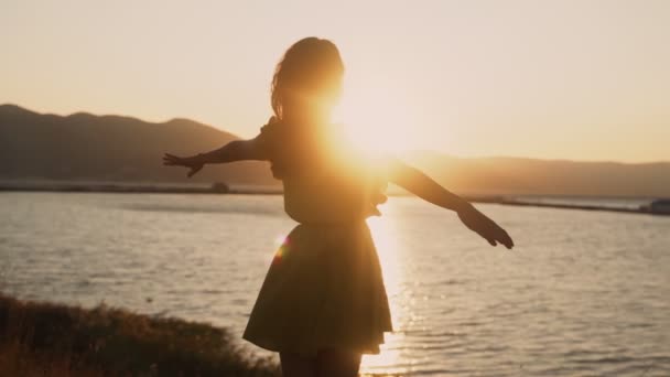 Σιλουέτα της νεαρής γυναίκας διαδίδει τα χέρια της ορθάνοιχτα σε χρυσό ηλιοβασίλεμα, αργή κίνηση — Αρχείο Βίντεο