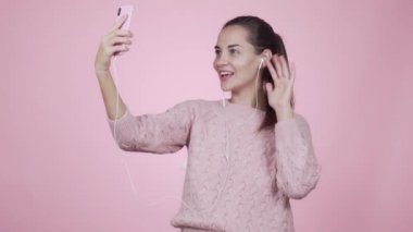 Pembe arka planda izole edilmiş cep telefonu kullanan bir kadın görüntülü konuşma yapıyor