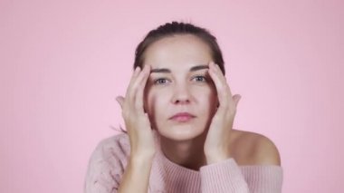 Kameraya bakan bir kadın, pembe arka planda saçlarını düzelten bir ayna gibidir.