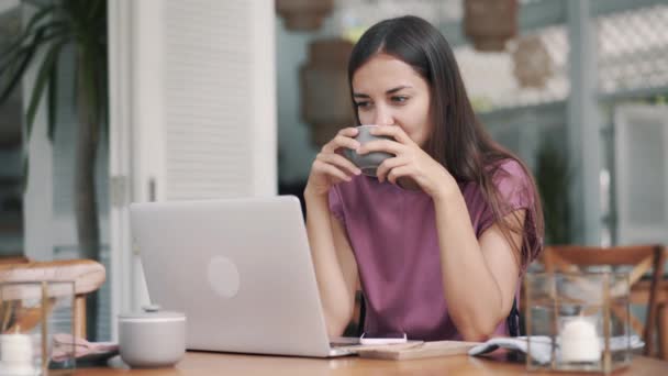 Πορτρέτο της νεαρής γυναίκας που κάθεται με laptop και ποτά καφέ στο καφέ — Αρχείο Βίντεο