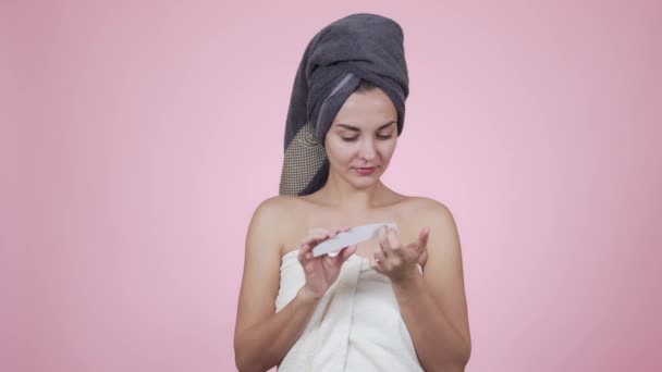 Vrouw in bad handdoek maakt manicure met nagel bestand geïsoleerd op roze achtergrond — Stockvideo