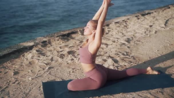 Femme fait des exercices de yoga, s'étend le matin avec vue sur l'océan, au ralenti — Video