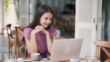 Kafede güzel bir kızın portresi. Bilgisayarlı web kamerası aracılığıyla video bağlantısıyla konuşuyor.