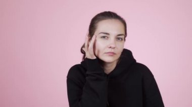 Kameraya bakan bir kadın, pembe arka planda saçlarını düzelten bir ayna gibidir.
