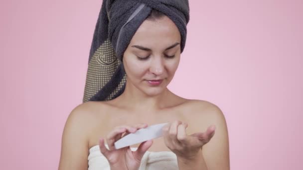 Mulher em toalha de banho faz manicure com unha arquivo isolado no fundo rosa — Vídeo de Stock