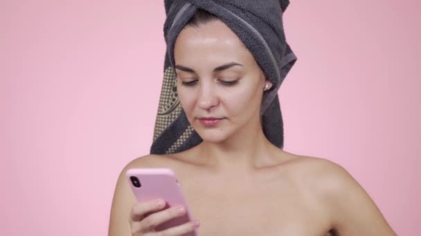 Mujer con toalla en la cabeza hablando por teléfono, aislada sobre fondo rosa — Vídeo de stock