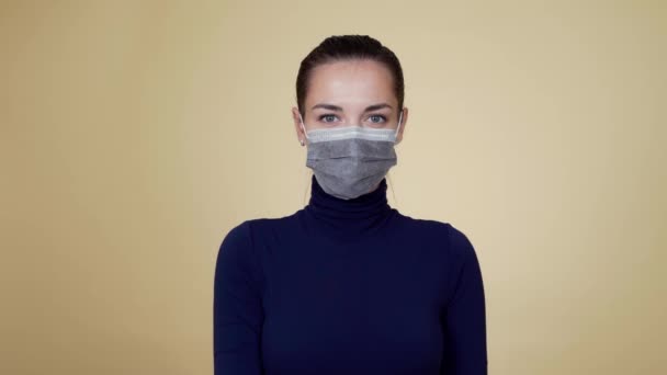 Kvinna i skyddande medicinsk mask sprayar desinfektionsmedel på kameran, coronavirus — Stockvideo