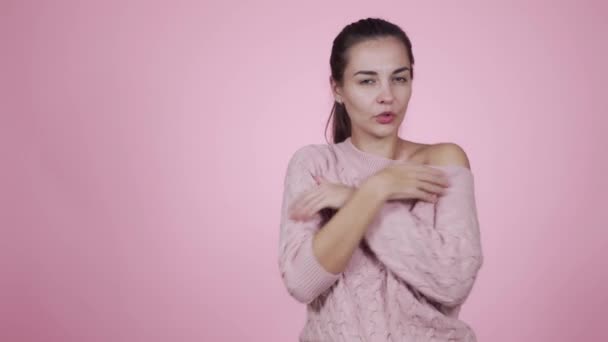 Woman wearing in knitted sweater freezes, feels cold isolated on pink background — Stock Video