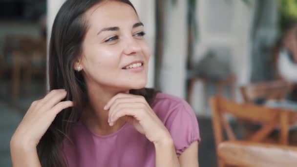 Портрет красивой женщины, сидящей в кафе, улыбающейся и смотрящей в камеру — стоковое видео