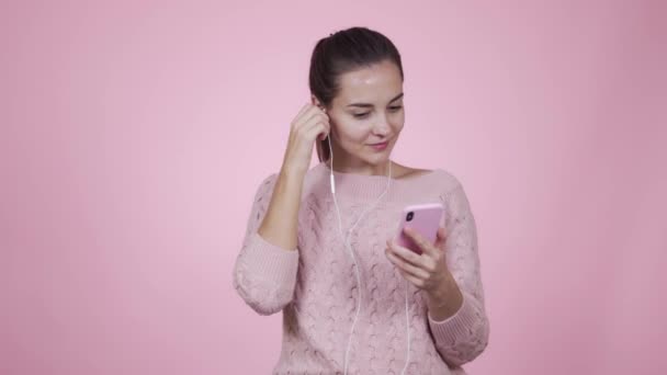 Young woman puts on earphones, listening music and enjoying song, isolated. — Stock Video