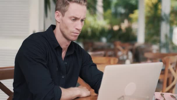 Hombre freelancer sentado en la mesa usando el ordenador portátil para el trabajo en la cafetería moderna — Vídeos de Stock