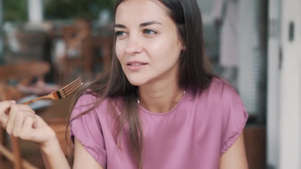 Portret van mooie vrouw eet groentesalade in cafe, op zoek naar camera — Stockvideo