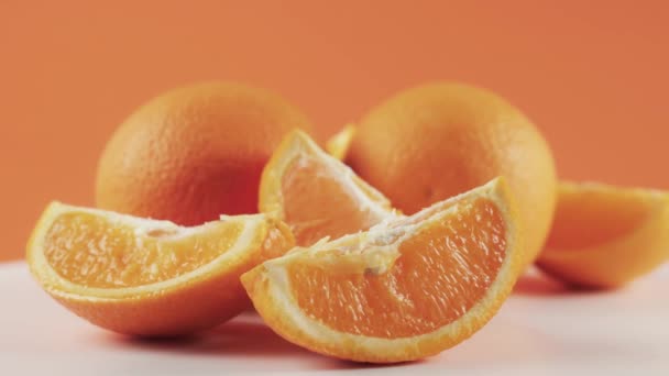 Zblízka, plátky pomeranče na bílém točícím se stole izolované na oranžovém pozadí — Stock video