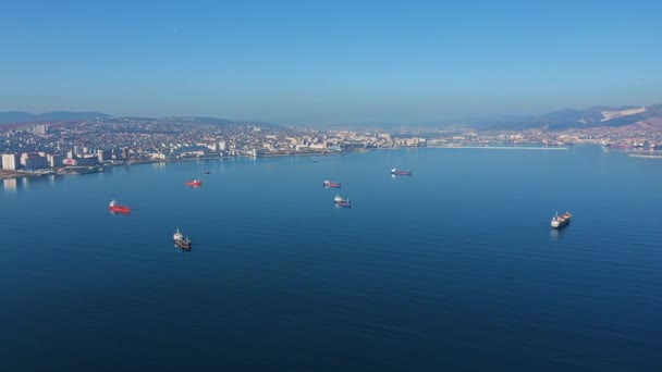Vista aérea, embarcações à deriva na calma superfície azul do oceano contra a cidade na costa — Vídeo de Stock