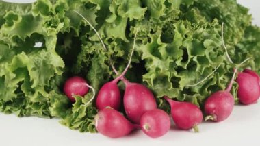 Beyaz arkaplanda izole edilmiş, dönen masada marul ve turpu kapat