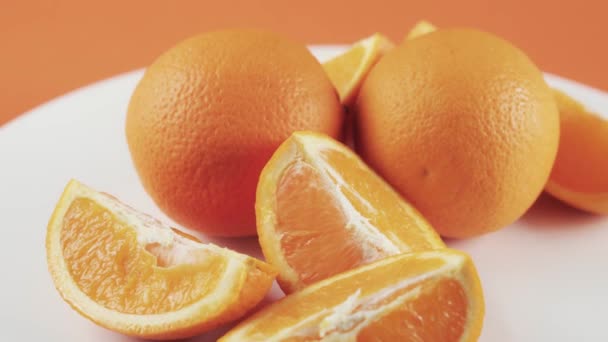 Primer plano, rodajas de naranja sobre mesa giratoria blanca aisladas sobre fondo naranja — Vídeos de Stock