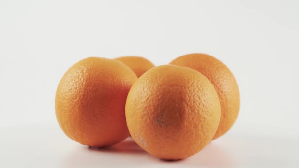 Cuatro naranjas maduras sobre mesa giratoria aislada sobre fondo blanco — Vídeos de Stock