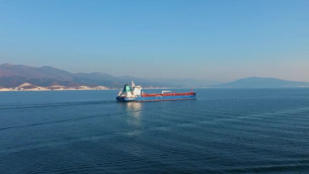 Luchtfoto van ultragroot vrachtschip op zee verlaat haven op zonnige dag — Stockvideo