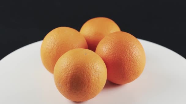 Gros plan, quatre oranges sur table tournante blanche isolées sur fond noir — Video