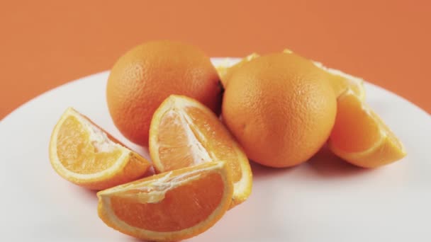 Rebanadas de naranja cortadas sobre mesa giratoria blanca aislada sobre fondo naranja — Vídeos de Stock