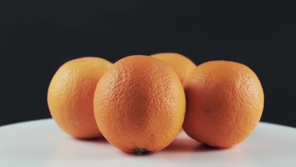 Cerca, cuatro naranjas maduras sobre mesa giratoria blanca aislada sobre fondo negro — Vídeos de Stock