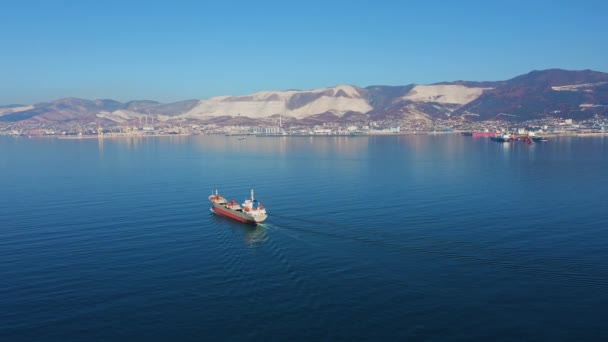 Vista aérea del buque de carga ultra grande en el mar sale del puerto en el día soleado — Vídeos de Stock